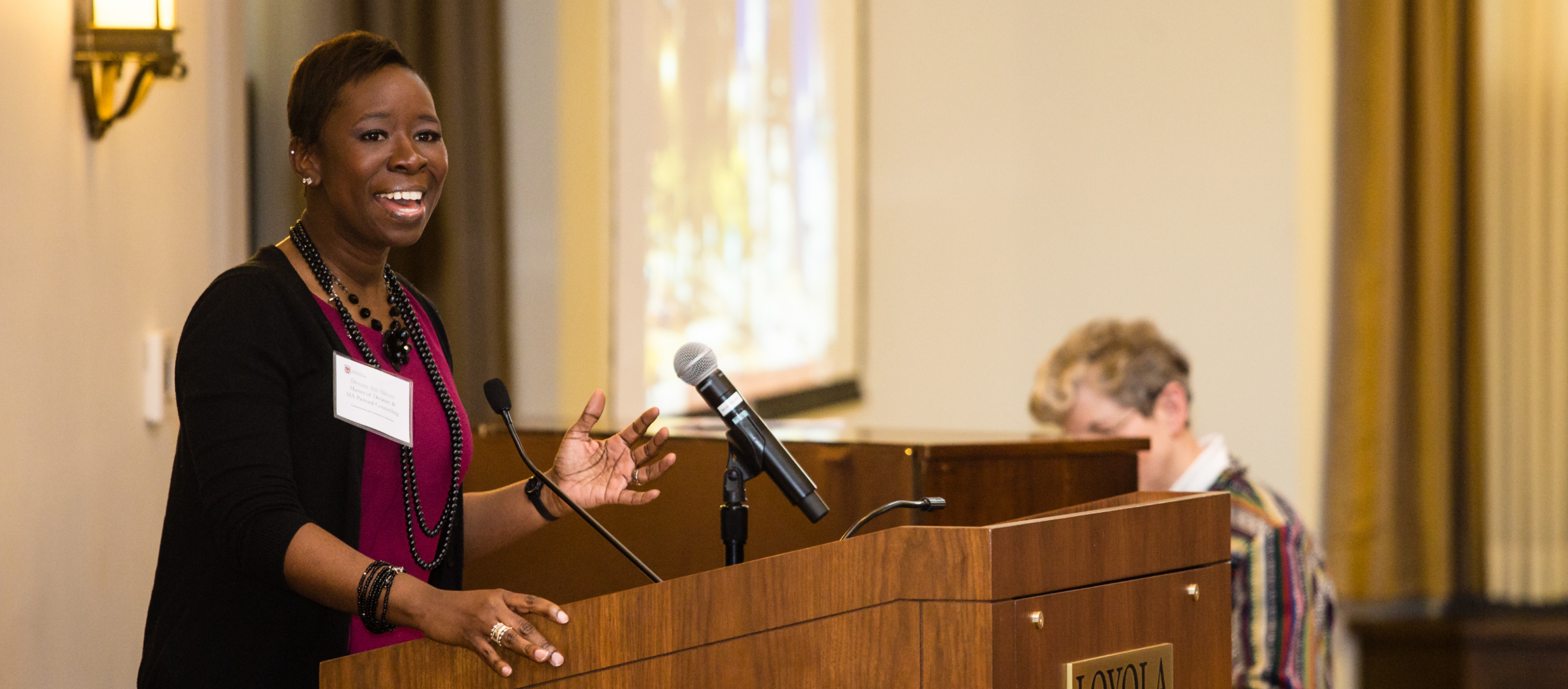 young woman at a podium speaking to an audience