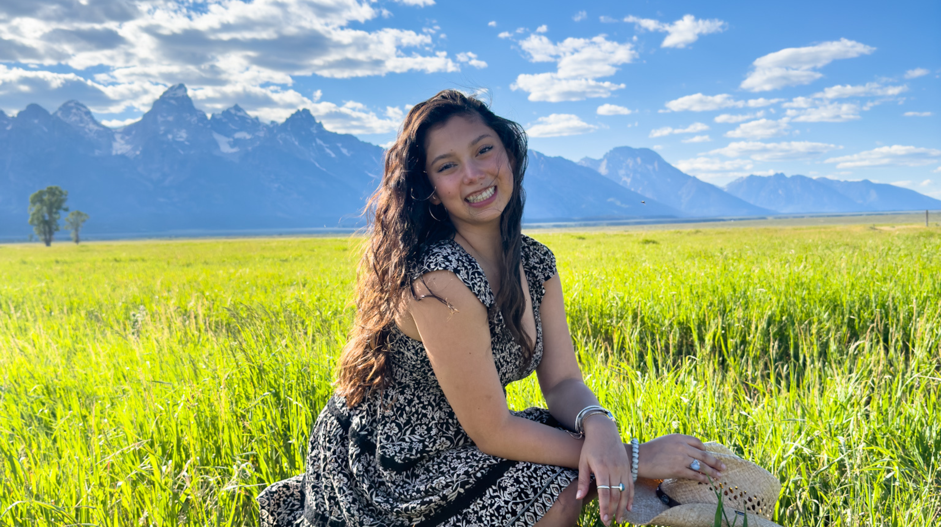 Sara Ruiz in a field of grass with mountains in the far background.