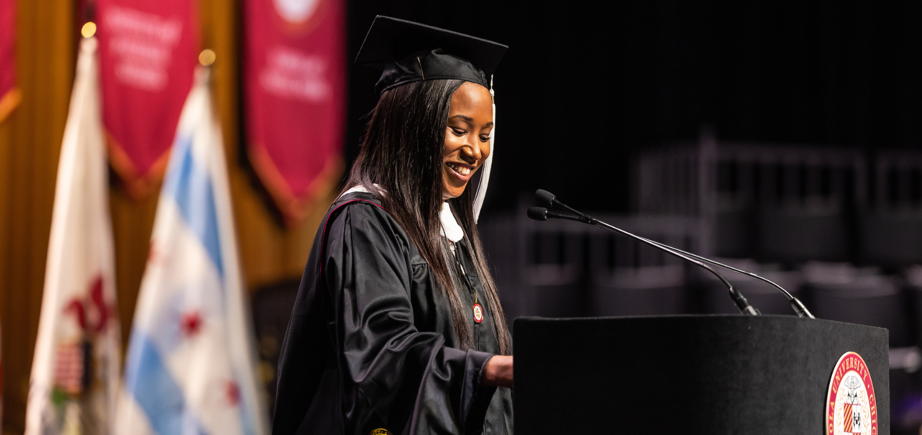 Krystal Westmoreland, dressed in graduation regalia, delivers her speech at the lectern on stage at the School of Continuing and Professional Studies 2024 Commencement Ceremony